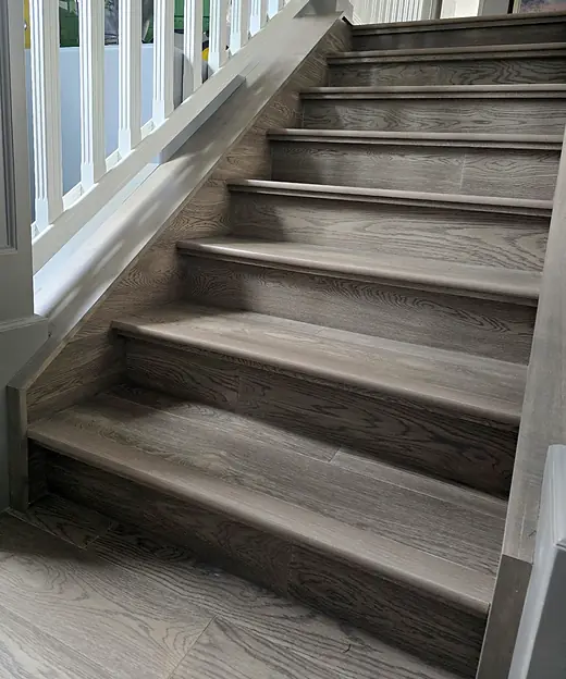 Gray-stained wood stair treads with matching flooring