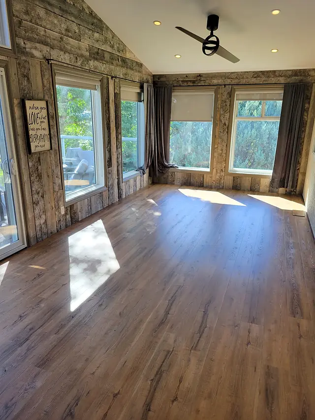 Vaulted living room with tall windows and warm plank flooring