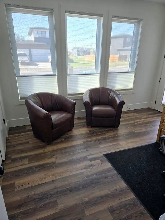 Sitting room with cellular shades on three windows and dark plank flooring