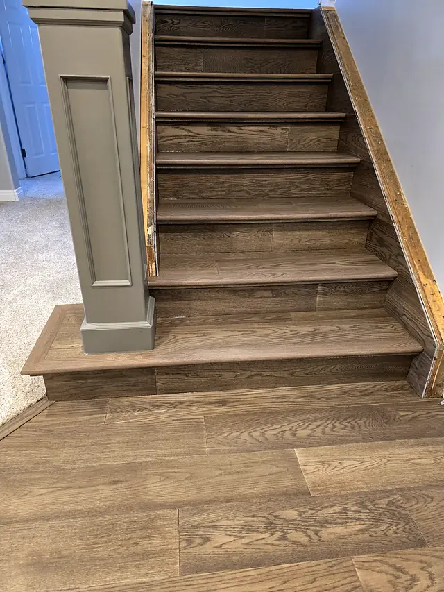 Gray wood staircase with a newel post and wide plank landing
