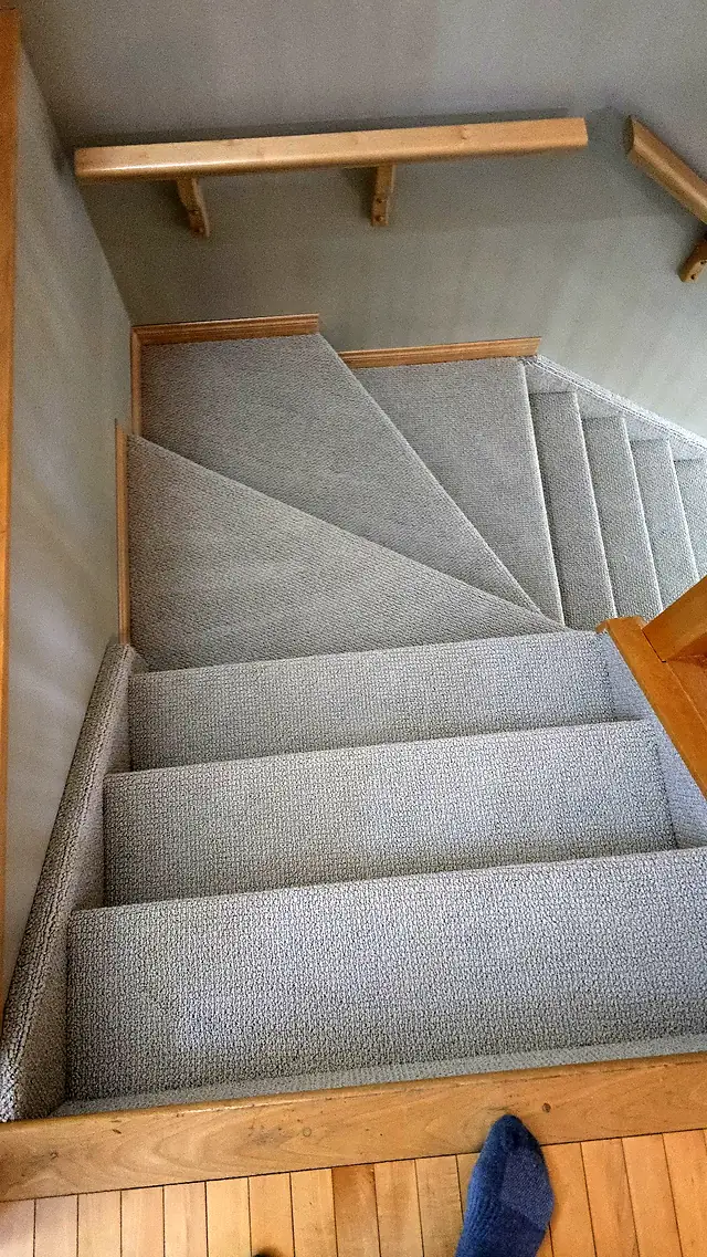 Carpeted staircase seen from above with wood accents